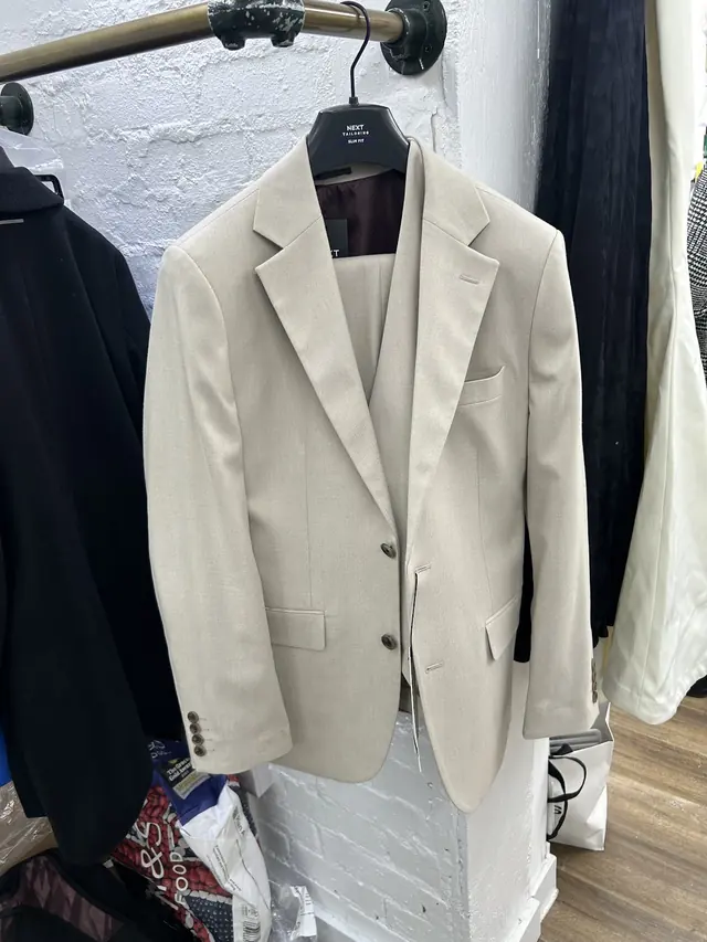 A cream single-breasted jacket hanging on the workshop rail